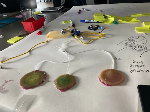 A table with 3, round soft robot actuators tied to an Arduino contraption